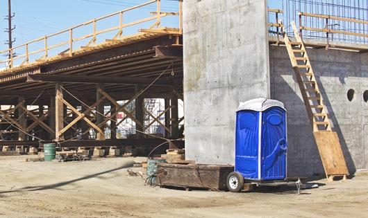 a clean and organized line of portable restrooms at a work site, keeping workers content